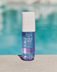 A bottle of Sweet Wave body mist with plum and vanilla orchid, placed near a poolside.
