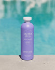 Purple bottle of Duples & Co. body wash with a pool in the background