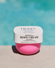 Pink body cream jar with white label against a blue background