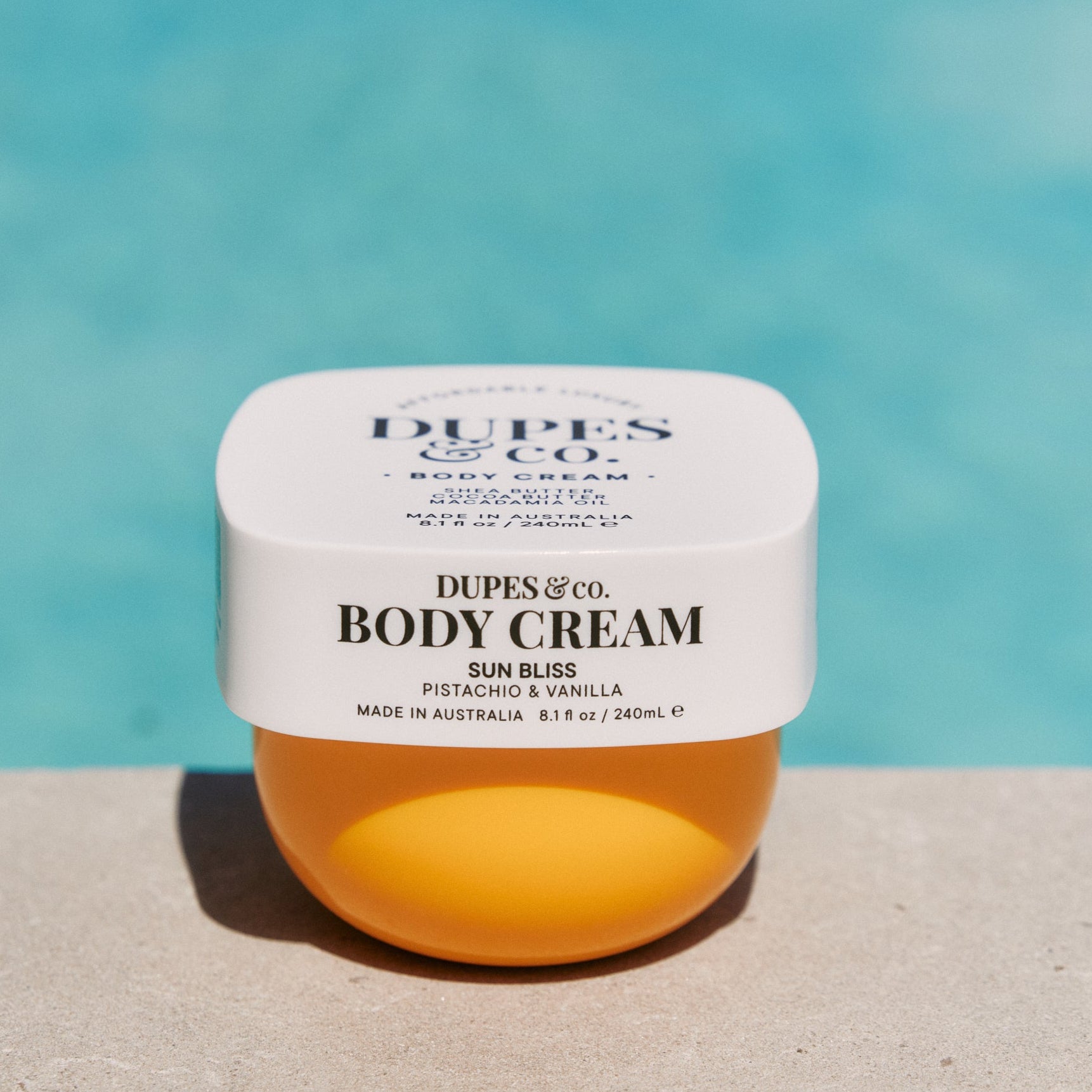 Jar of Dupes & Co. body cream with a blurred pool background