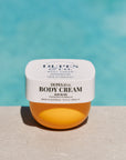 Jar of Dupes & Co. body cream with a blurred pool background