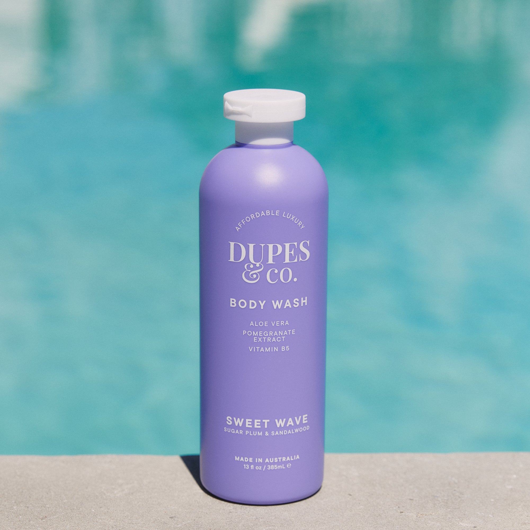 Purple bottle of Duples & Co. body wash with a pool in the background