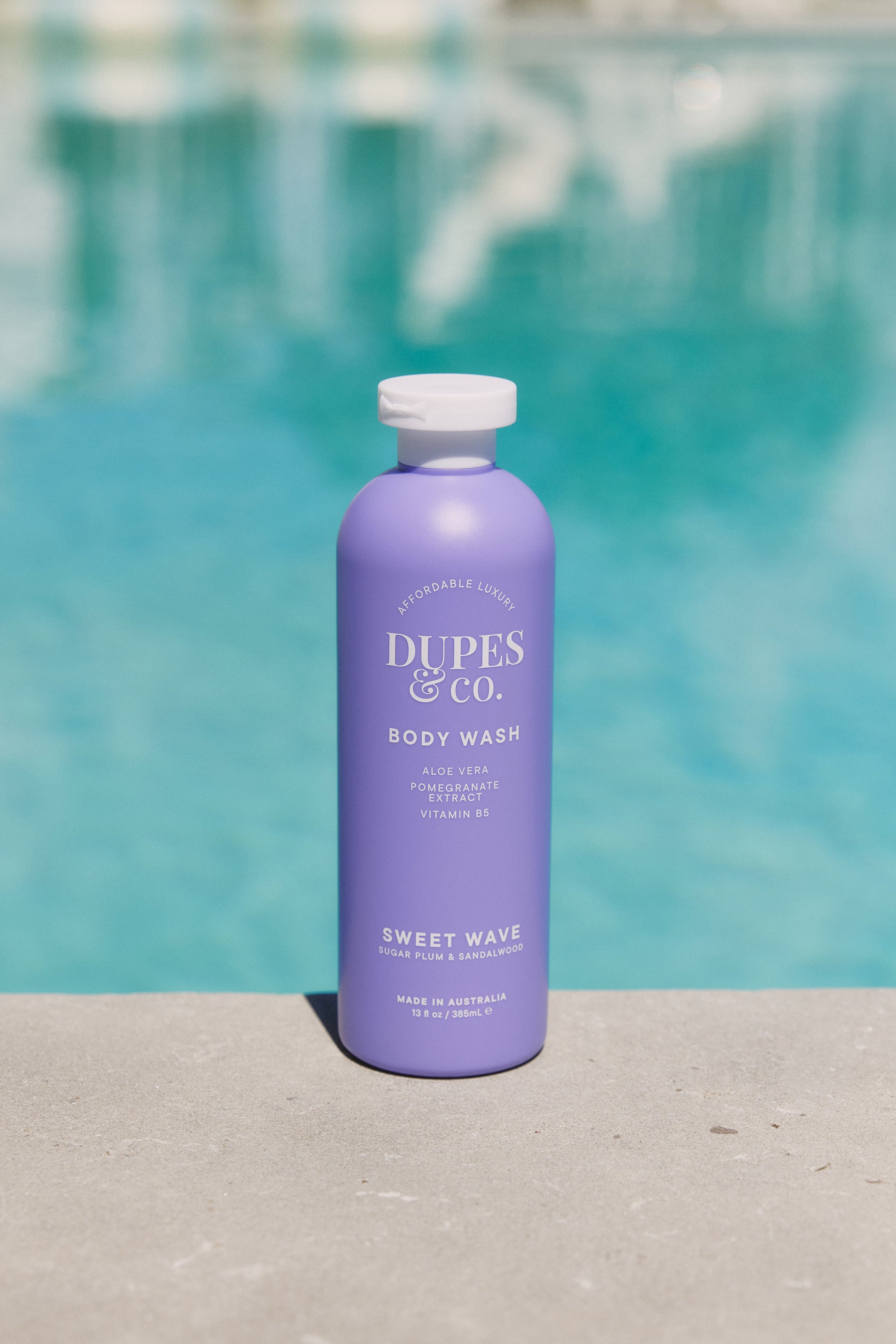Purple bottle of Duples & Co. body wash with a pool in the background
